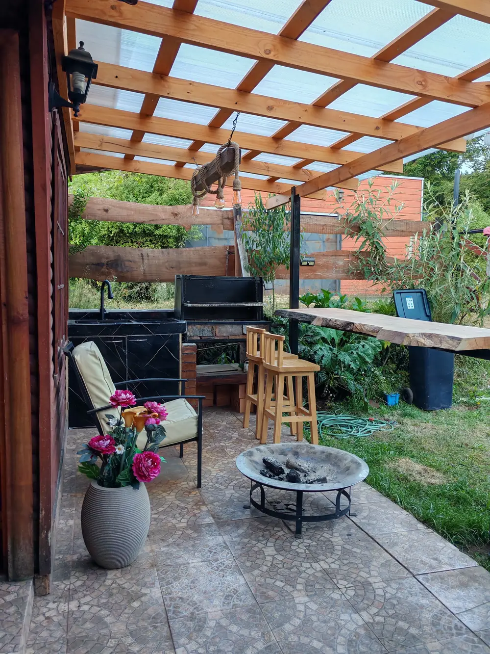 Quincho techado con parrilla, banquetas de madera y fogón